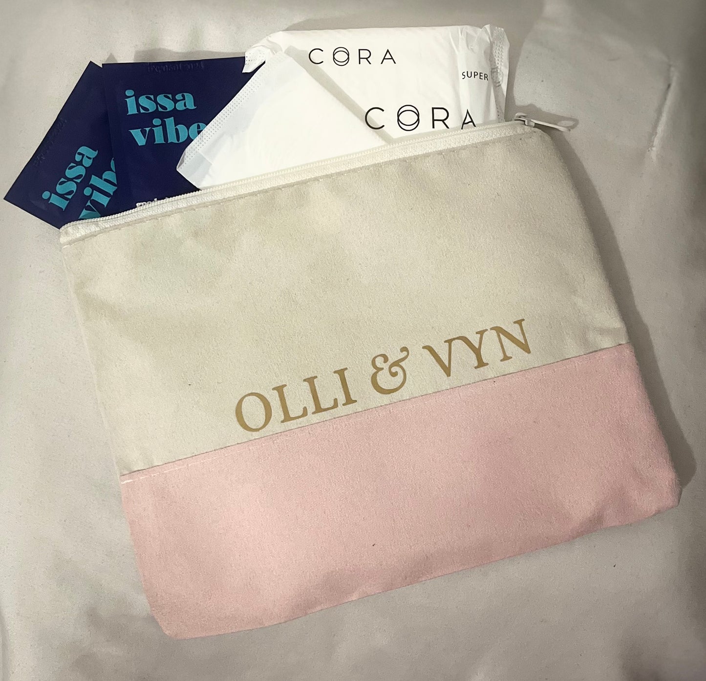 off white and pink suede period kit bag with company name in gold. period kit products including period pad, wipes and period liner