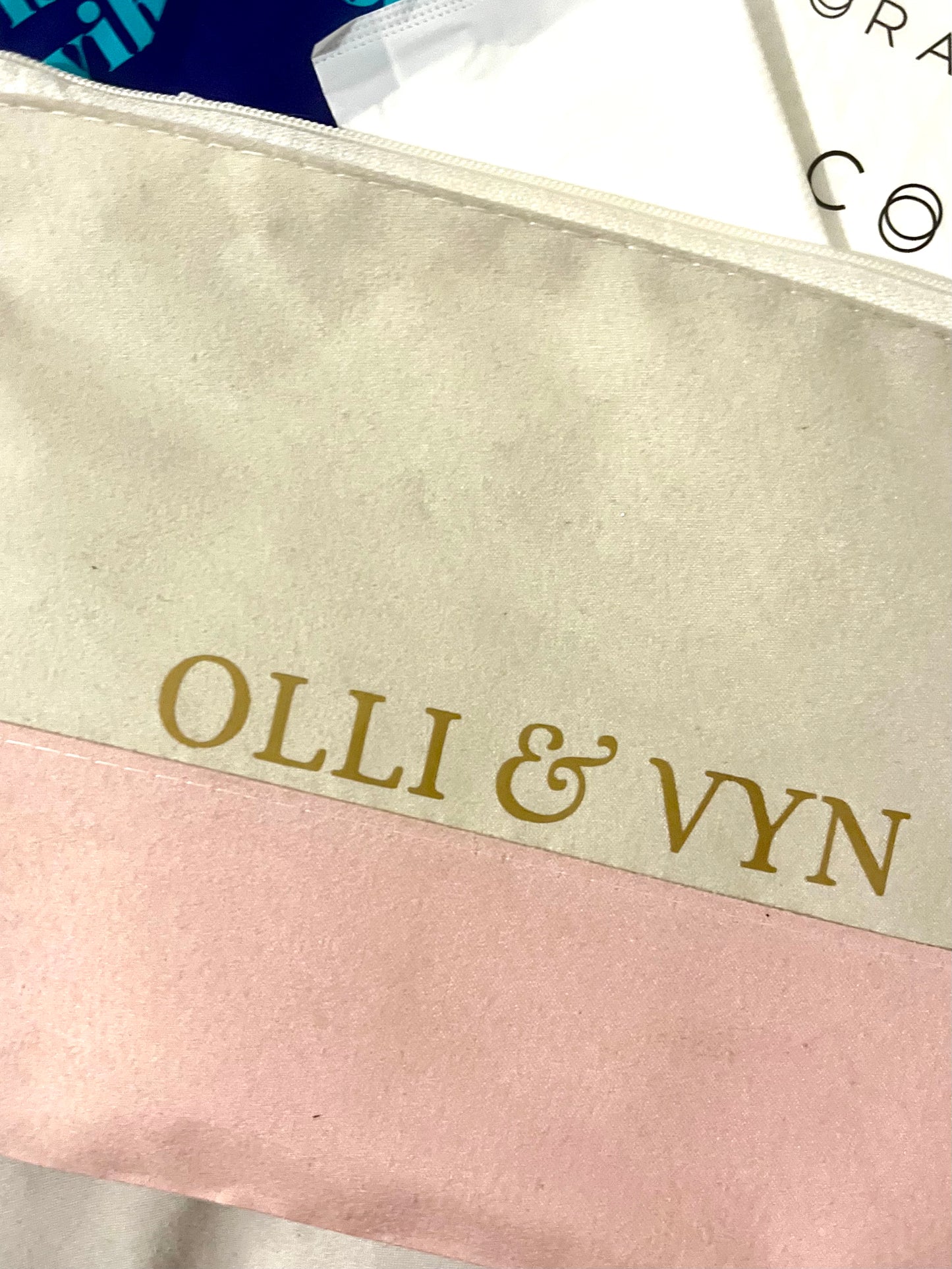 off white and pink suede period kit bag, branded with the company's name in gold. Containing period products